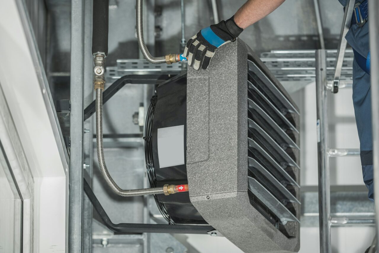 Technician Servicing Warehouse Heating Unit Attached to Building Wall